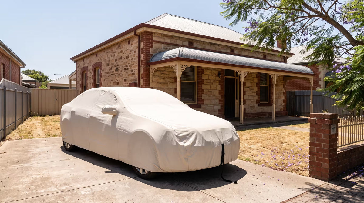 Off white custom outdoor car cover strapped down on a sedan in full sun outside an Adelaide villa